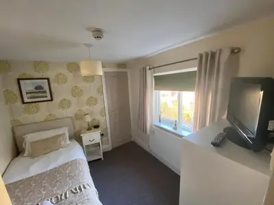 a bedroom with a bed and a tv and a window at The Queens in St Bees