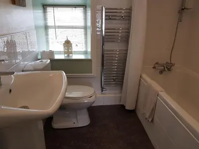 a bathroom with a sink and a toilet and a tub at The Queens in St Bees