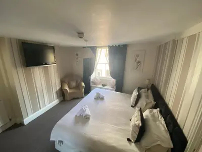 a bedroom with a large white bed and a chair at The Queens in St Bees