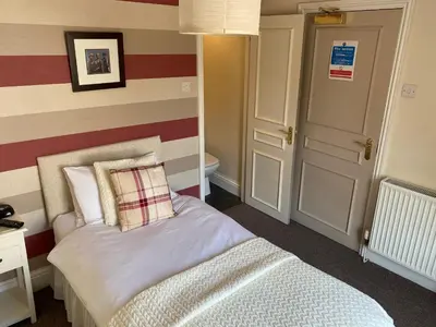 a bedroom with a bed and a striped wall at The Queens in St Bees
