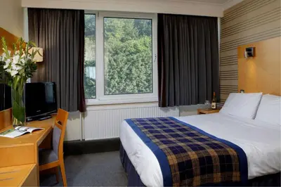 a hotel room with a bed and a desk and a television at Best Western Palace Hotel & Casino in Douglas