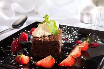 a piece of chocolate cake with fruit on a black plate at Best Western Palace Hotel & Casino in Douglas