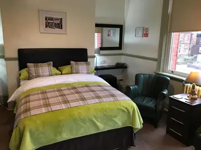 a bedroom with a bed and a chair and a window at Abberley House in Carlisle