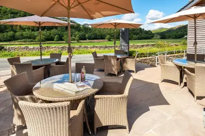 a patio with tables and chairs with umbrellas at The Lodge In The Vale in Thirlmere