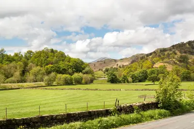 a field of green grass with mountains in the background at The Lodge In The Vale in Thirlmere