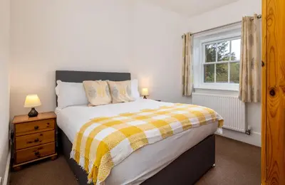 a bedroom with a bed with a yellow and white blanket at Muncaster Castle Coachman's Quarters in Ravenglass