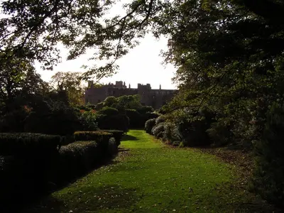 a path through a garden with a castle in the background at Muncaster Castle Coachman's Quarters in Ravenglass