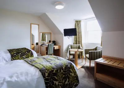 a hotel room with a bed and a desk and chairs at Selkirk Arms Hotel in Kirkcudbright