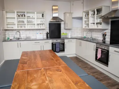a kitchen with white cabinets and a wooden table at YHA Keswick in Keswick
