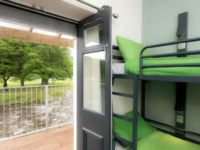 a room with bunk beds and a balcony at YHA Keswick in Keswick