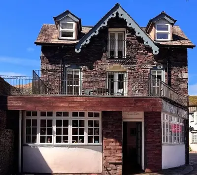an old brick building with a balcony on top at Jacksons CafeBar & Guesthouse in Grasmere