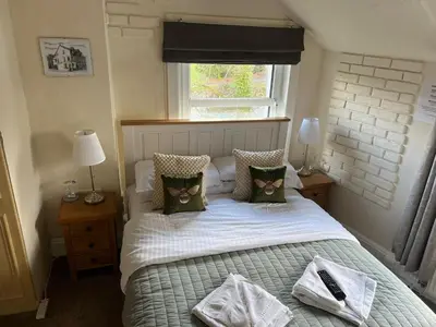 a bedroom with a bed with pillows and a window at Babbling Brook Guesthouse in Keswick