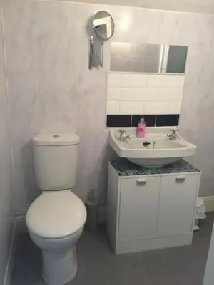 a white bathroom with a toilet and a sink at Babbling Brook Guesthouse in Keswick