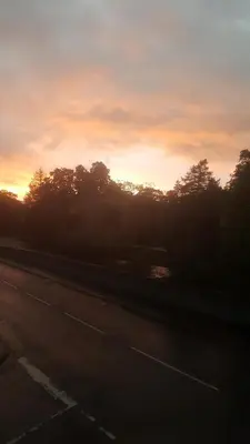 a sunset over a road with trees in the background at Babbling Brook Guesthouse in Keswick
