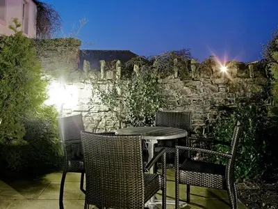 an outdoor table with chairs and a stone wall at Trout Hotel in Cockermouth