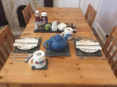 a wooden table with a teapot and dishes on it at Dolly Waggon Guest House in Keswick