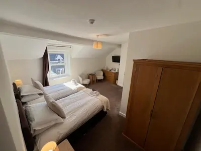 a bedroom with a large bed and a wooden cabinet at Dolly Waggon Guest House in Keswick