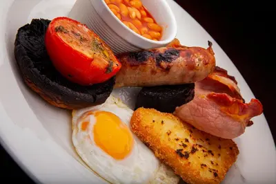 a plate of breakfast food with eggs bacon and beans at The Pheasant Inn - The Inn Collection Group in Bassenthwaite