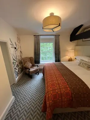 a bedroom with a bed and a chair and a window at Royal Oak Hotel in Rosthwaite