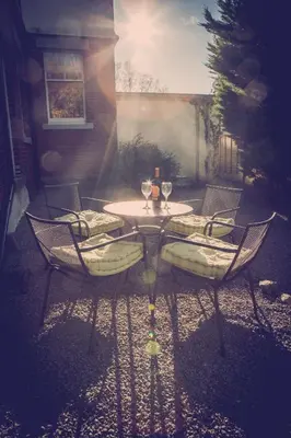a table and chairs with wine glasses on a patio at The Garden Apartment in Keswick
