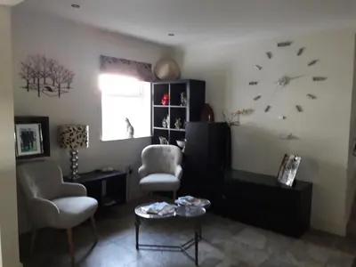 a living room with a couch and a clock on the wall at At Cedar Lodge in Ramsey