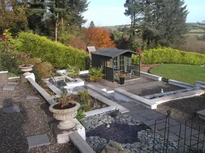 a garden with a small cabin in the background at At Cedar Lodge in Ramsey