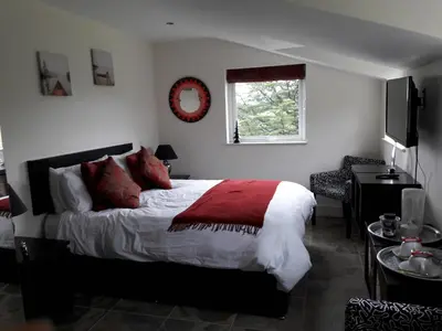 a bedroom with a bed with a red blanket and a window at At Cedar Lodge in Ramsey