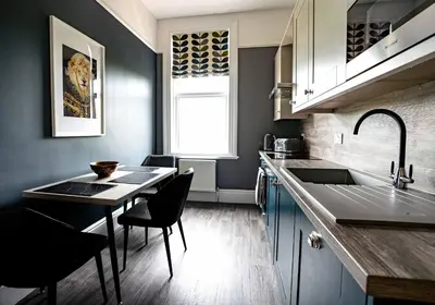 a kitchen with a table and chairs and a sink at Amadeus Apartments in Douglas