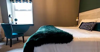 a bedroom with a bed with a black fur blanket on it at Amadeus Apartments in Douglas