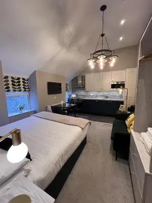 a bedroom with a large bed and a kitchen at Amadeus Apartments in Douglas