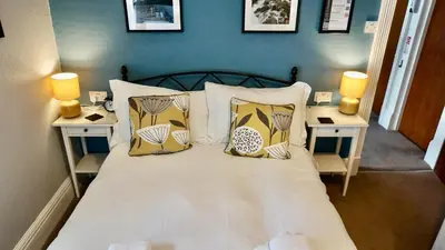 a bedroom with a bed with pillows and two tables at Greystoke House in Keswick