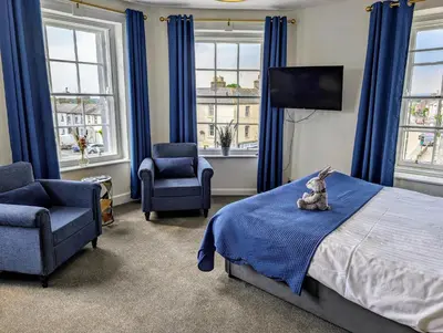 a bedroom with blue curtains and a bed and two chairs at Graham Arms Inn in Longtown