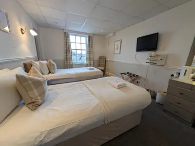 a hotel room with two beds and a flat screen tv at Graham Arms Inn in Longtown