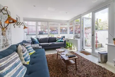 a living room with a blue couch and a table at Rivendell Cottage in Douglas
