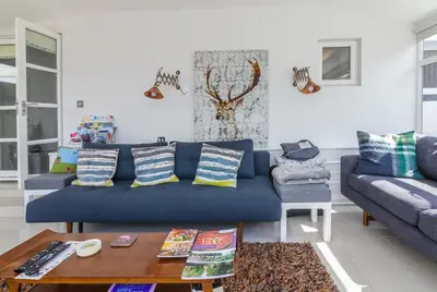 a living room with a blue couch and a table at Rivendell Cottage in Douglas
