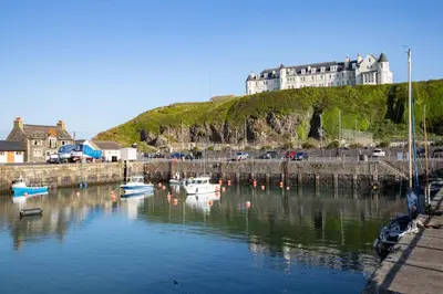 a marina with boats in the water with a large building at The Portpatrick Hotel by Compass Hospitality in Portpatrick