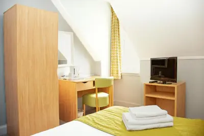 a bedroom with a bed and a desk and a television at The Portpatrick Hotel by Compass Hospitality in Portpatrick