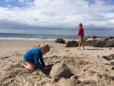 two children playing in the sand on the beach at Woodcroft Cottage in Ayr