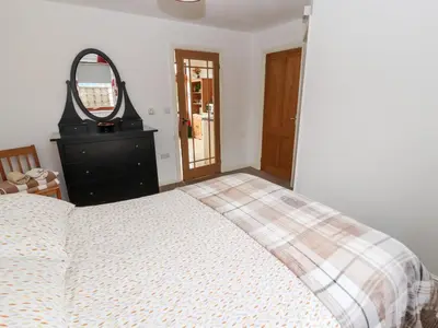 a bedroom with a bed and a dresser and a mirror at Nuthatch in Ivegill