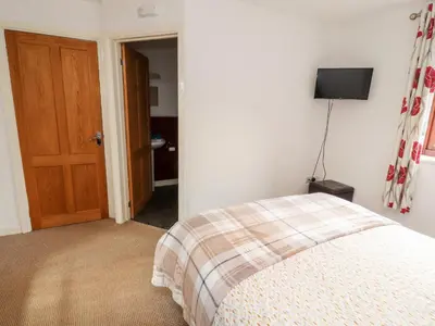 a bedroom with a bed and a wooden door at Nuthatch in Ivegill