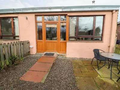 a house with a wooden door and a table at Nuthatch in Ivegill