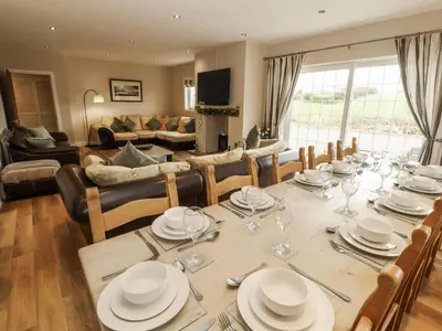 a dining room with a table and a living room at White Gables in Great Clifton