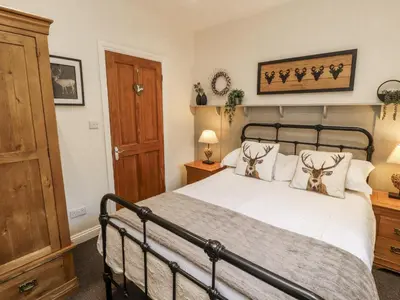 a bedroom with a bed with two animals on the pillows at White Gables in Great Clifton