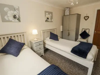 a bedroom with two beds and a lamp on a table at White Gables in Great Clifton