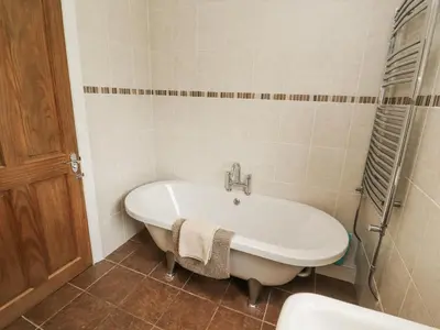 a bathroom with a bath tub and a sink at White Gables in Great Clifton