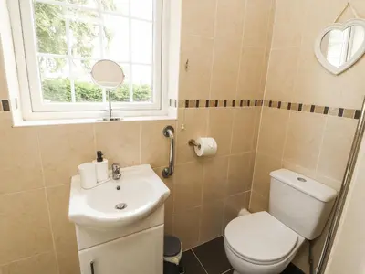a bathroom with a toilet and a sink and a window at White Gables in Great Clifton