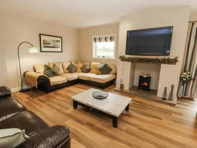 a living room with a couch and a tv at White Gables in Great Clifton