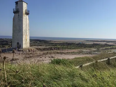 a lighthouse sitting on top of a sandy beach at Kouloura in Mainsriddle