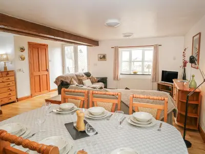 a living room with a table and chairs and a couch at Bleng Barn Cottage in Seascale