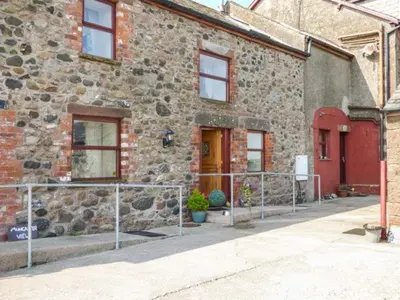 a stone building with a fence in front of it at Muncaster View in Drigg